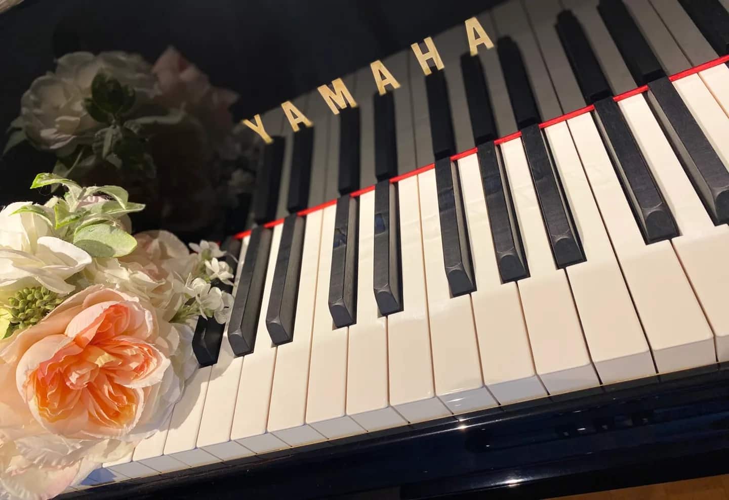 花が添えられたグランドピアノの鍵盤