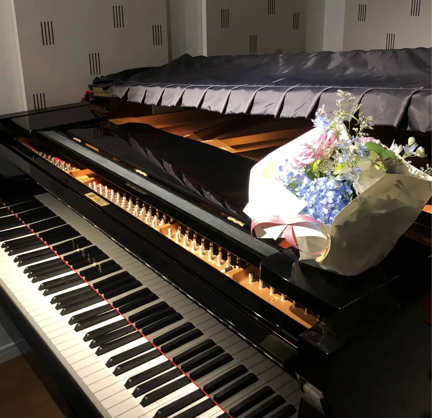 花束が置かれた防音室のグランドピアノ